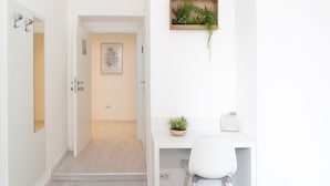 A modern, minimalist room with a white desk, a chair, a small potted plant, and a framed artwork on the wall. - White Gioberti Guesthouse (Rome)