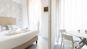 A hotel room with a bed, a small table with chairs, and a view through a glass door. - White Gioberti Guesthouse (Rome)