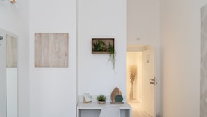 A modern, minimalist hallway with a white desk, a framed picture, a small plant, and a door labeled "206". - White Gioberti Guesthouse (Rome)