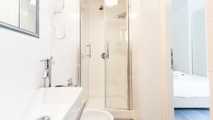 A modern bathroom with a glass-enclosed shower, a white sink, and a toilet. - White Gioberti Guesthouse (Rome)