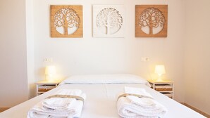 Habitación de hotel con cama, dos mesitas de noche y tres obras de arte en la pared.