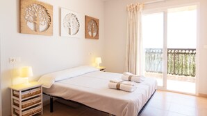 Una habitación de hotel con cama, lámparas de noche, ventana con cortinas y una obra de arte en la pared.