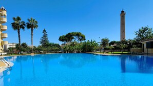Una piscina azul cristalina rodeada de palmeras y una torre alta.