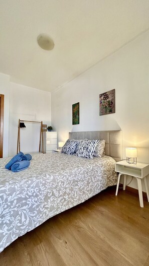 Een slaapkamer met een bed, nachtkastjes, een kledingkast en een kledingrek.