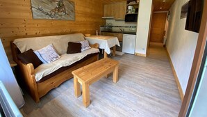 En mysig trästuga med en soffa, ett litet bord och ett litet kök.
