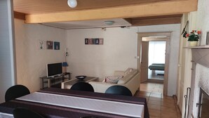 Un salón acogedor con sofá, una mesa de comedor con sillas, televisor y chimenea.