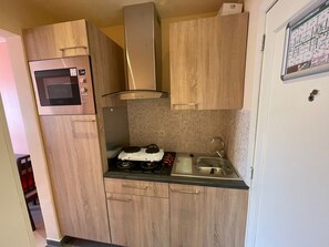 A compact kitchen with a built-in microwave, a gas stove, and a sink.