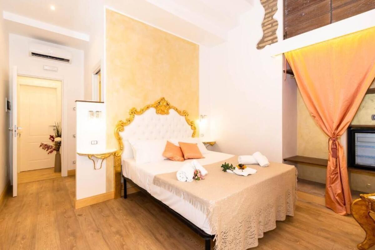 A hotel room with a bed, a bedside table, a lamp, and a television.