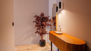 Ein Badezimmer mit einem Holzwaschtisch, einer Topfpflanze, einem Spiegel und einer Leuchte.