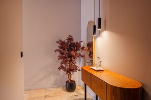 A bathroom with a wooden vanity, a potted plant, and a mirror. - Retreat Studio in Bolhão Market (Oporto)