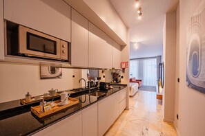 A modern kitchen with a built-in microwave, a coffee machine, and a sink. - Retreat Studio in Bolhão Market (Oporto)