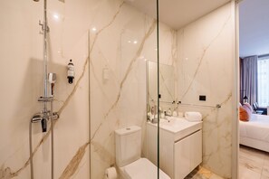 A modern bathroom with a glass shower enclosure, a toilet, a sink, and a mirror. - Retreat Studio in Bolhão Market (Oporto)