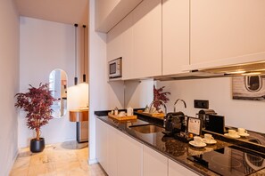 A modern kitchen with a built-in microwave, a coffee machine, and a sink. - Retreat Studio in Bolhão Market (Oporto)