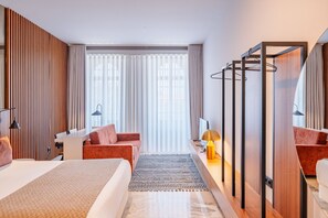 A hotel room with a bed, a desk, a chair, a mirror, and a window with curtains. - Retreat Studio in Bolhão Market (Oporto)