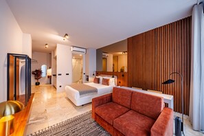 Ett modernt hotellrum med en säng, en soffa, ett skrivbord och en väggpanel i trä.
