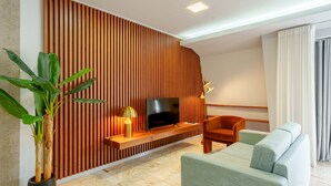 A modern living room with a TV, sofa, and potted plant.
