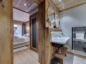 A wooden interior with a bed, a sink, and a mirror.
