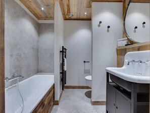 A modern bathroom with a bathtub, toilet, and vanity.