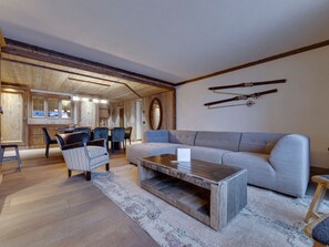 A spacious living area with a sofa, chairs, a coffee table, and skis mounted on the wall.