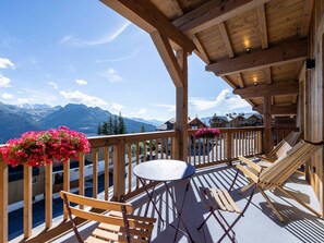 A wooden deck with a table and chairs, overlooking a mountainous landscape. - Modern apartment, terrace - 8 guests (Montvalezan-La Rosière)