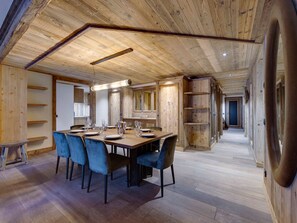 A dining area with a wooden table, blue chairs, and a modern pendant light.