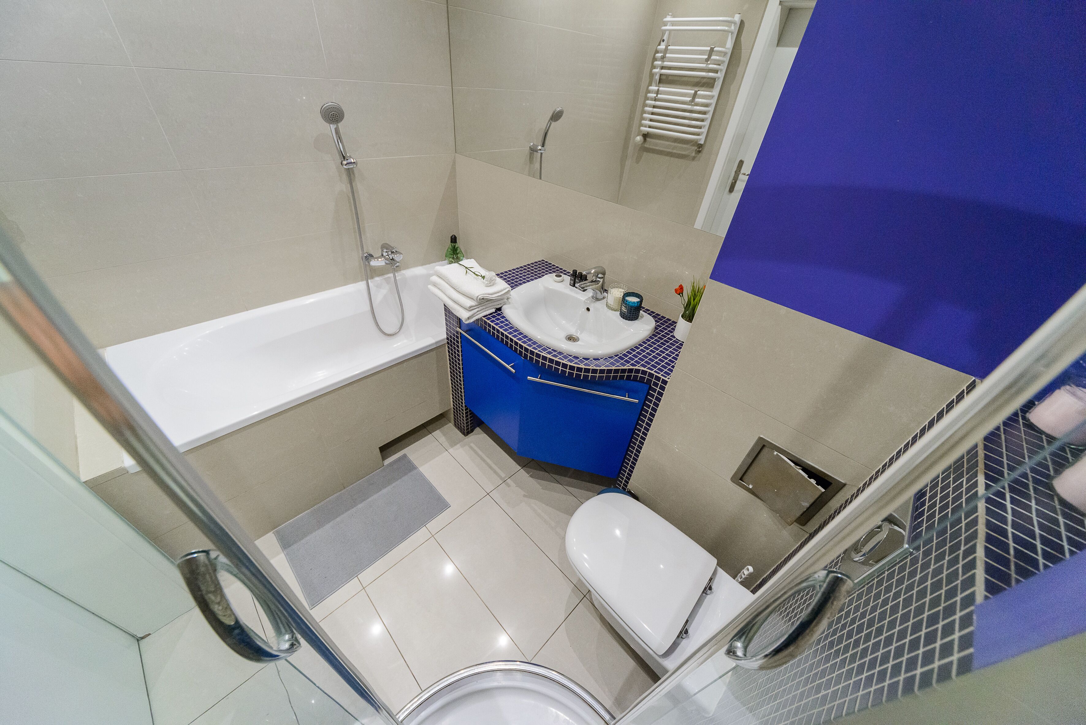 A bathroom with a white bathtub, a sink with a blue countertop, and a white toilet.