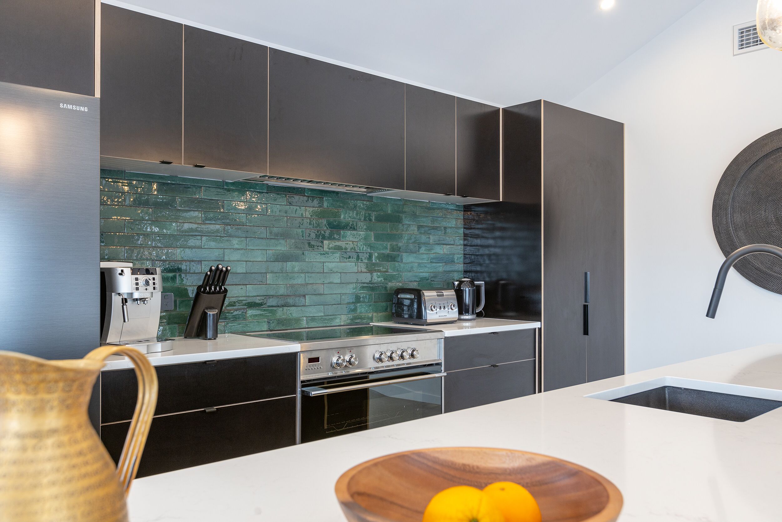 Una cocina moderna con un refrigerador de acero inoxidable, una cafetera, un tostador y un lavamanos.