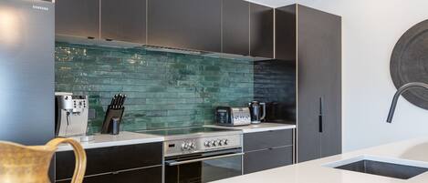 Una cocina moderna con un refrigerador de acero inoxidable, una cafetera, un tostador y un lavamanos.