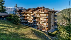 Un hotel de varios pisos con balcones y un paisaje montañoso al fondo.