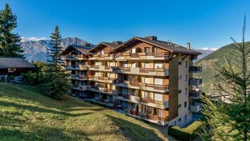 Un hôtel à plusieurs étages, doté de balcons et situé dans un cadre montagneux.