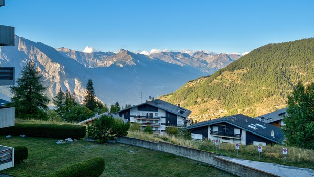 Una zona residencial con casas, cielo despejado y montañas al fondo.