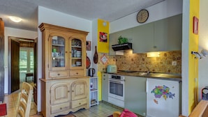 A compact kitchen with a wooden cabinet, a small oven, and a refrigerator with a map decoration. - Appartement Savoleyres 30 - La Tzoumaz, 4 Vallees (La Tzoumaz)