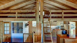A rustic cabin interior with a high ceiling, wooden beams, a kitchen area, and a staircase leading to a loft. - Chalet Bellevue - Jacuzzi - Views - La Tzoumaz, 4 Vallees (La Tzoumaz)