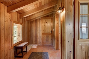 Un couloir intérieur aux murs en bois, avec un banc, une porte et une fenêtre.
