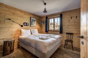 Quarto com painéis de madeira, uma cama, uma cadeira, uma janela e um ventilador de teto.