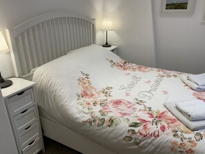 Un lit bien fait, avec une couvre-lit à motifs floraux et une serviette posée sur le côté.