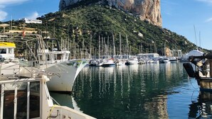 A marina with boats docked, a prominent rocky hill in the background, and a clear blue sky. - Genuine Spanish villa - large private pool - close to the beach - sun all day (Benissa)