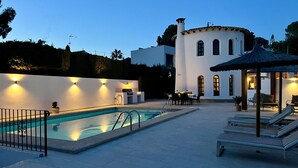 A pool area with a lounge chair and umbrella, a barbecue, and a white building with arched windows. - Genuine Spanish villa - large private pool - close to the beach - sun all day (Benissa)