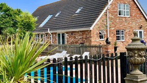 A brick house with a sloped roof, a fenced pool area, and a statue.