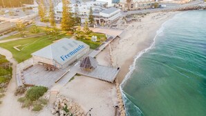 Ein Hotel direkt am Strand, mit einem gut sichtbaren 'Fremantle'-Schild, feinem Sandstrand und einer felsigen Küstenlinie.
