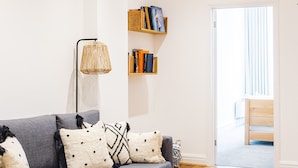 A modern living room with a grey sofa, patterned cushions, a floor lamp, and built-in bookshelves. - 2 Bed Apartment Right on Trafalgar Square  (London)
