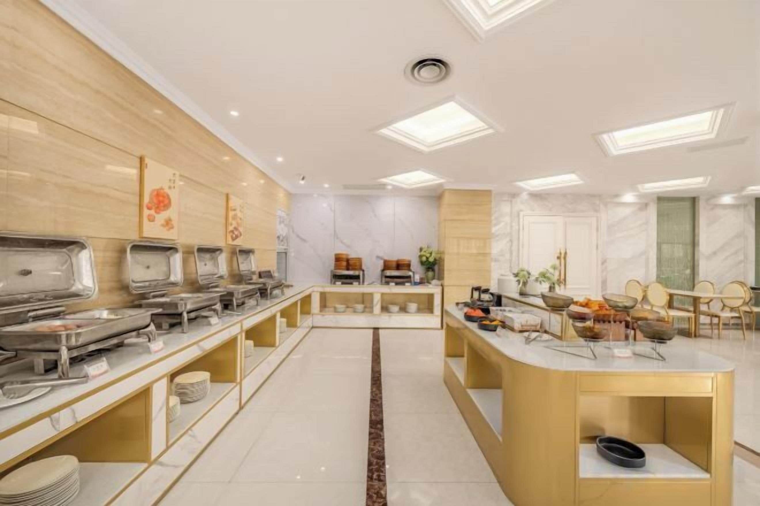 A hotel dining area with buffet stations, seating arrangements, and a central serving counter.