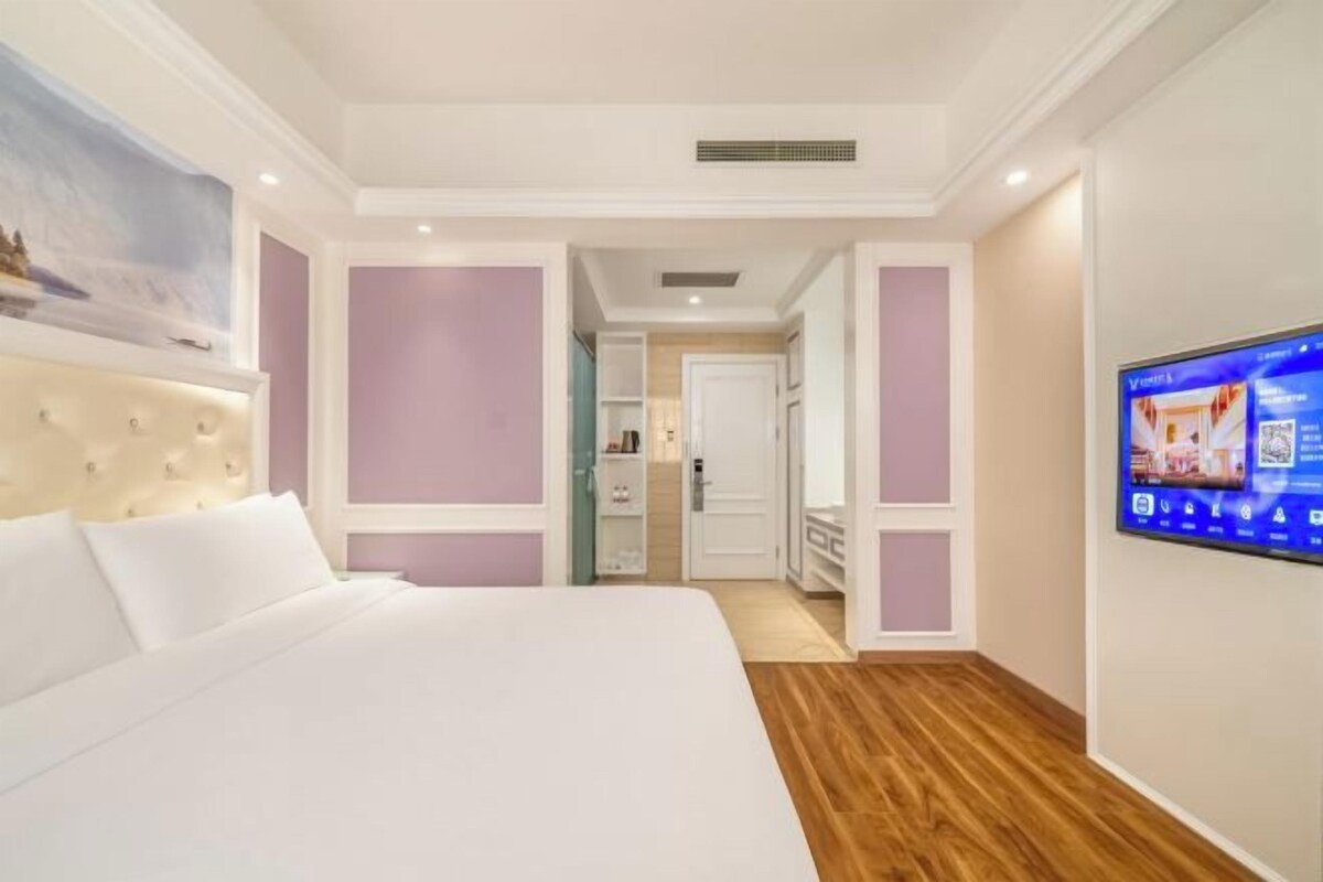 A hotel room with a large bed, a television, and a bathroom visible through an open door.