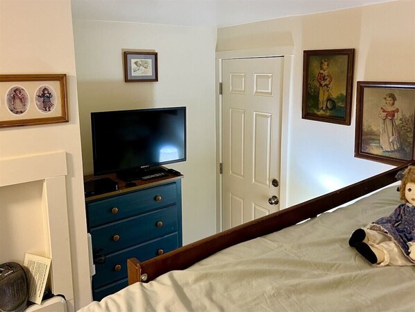 A bedroom with a bed, a dresser, a television, and framed pictures on the wall.