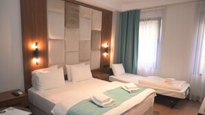 Une chambre d’hôtel avec deux lits, une tête de lit en bois, une table de chevet, un bureau et une fenêtre avec des rideaux.