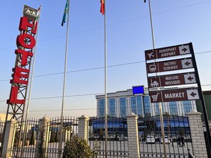 Un letrero de hotel con indicaciones hacia el aeropuerto, el metro, la mezquita Masjid y el mercado.