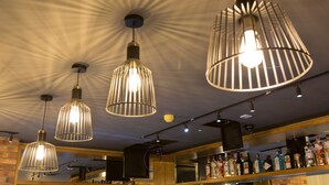 A bar area with hanging pendant lights and a shelf of liquor bottles. - Castle Varagh Hotel & Bar (Castlepollard)