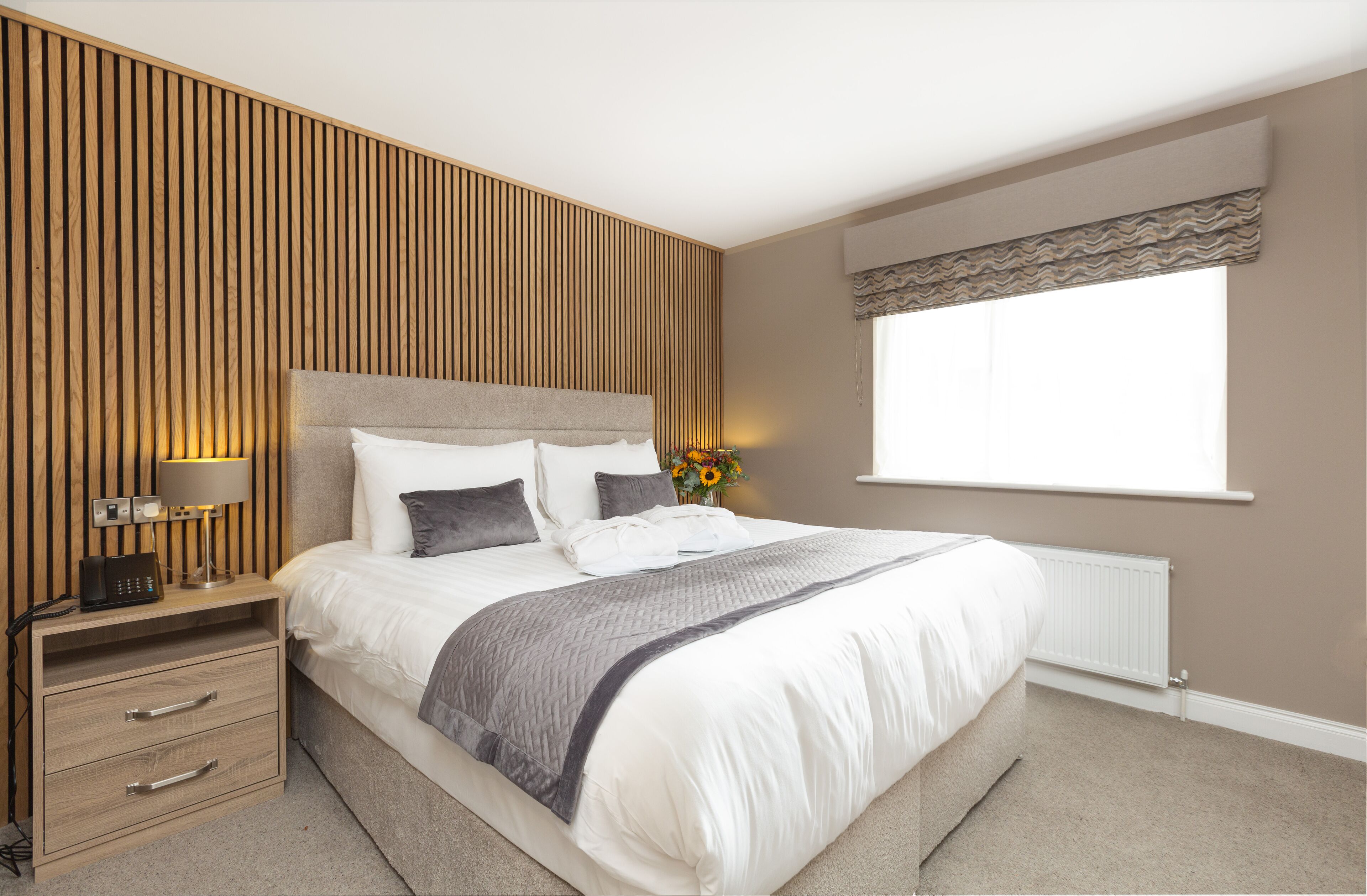 A bedroom with a bed, bedside tables, a lamp, and a window with curtains.