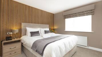 A bedroom with a bed, bedside tables, a lamp, and a window with curtains.