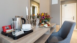 A hotel room with a wooden desk, a chair, a mirror, and a tray with coffee and snacks. - Castle Varagh Hotel & Bar (Castlepollard)